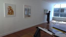 Andre Sampson helping with the hang; here seen with her own work and three portraits by Katrin Kampmann